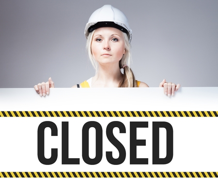 Worker holding closed sign placed on information boardの写真素材