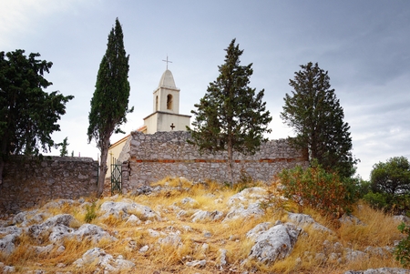 Old small church and stone walls on hillの写真素材