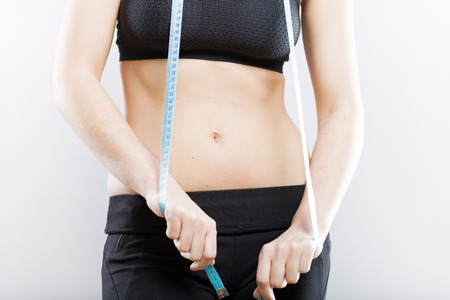 Young woman belly and measuring tape, weight loss conceptの写真素材