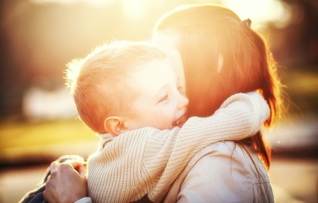 Mother hugging her child druing walk in the parkの写真素材