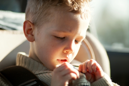 Child portrait of beautiful little boy sitting in car