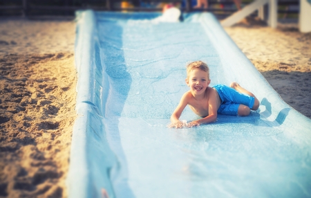 Child on water slide at aquapark during summer holidayの写真素材
