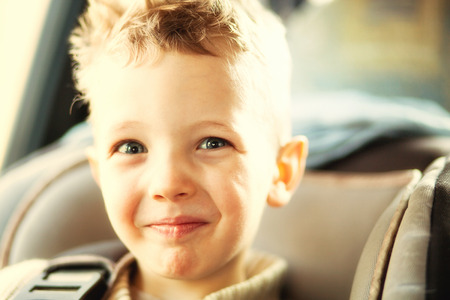 Child portrait of beautiful little boy sitting in carの写真素材