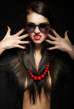 Glamour woman with dark shiny long hair, sunglasses and red beadsの写真素材