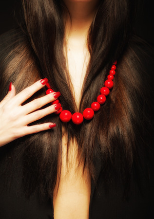 Red beads woman hand on neck and long dark hairの写真素材