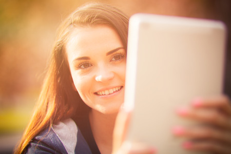 Beautiful girl using tablet or ebook outdoorの写真素材