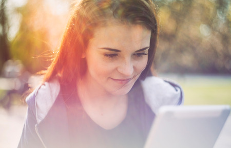 Beautiful girl using tablet or ebook outdoorの写真素材