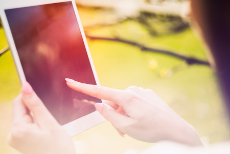 Girl using tablet or ebook outdoor, closeup screen