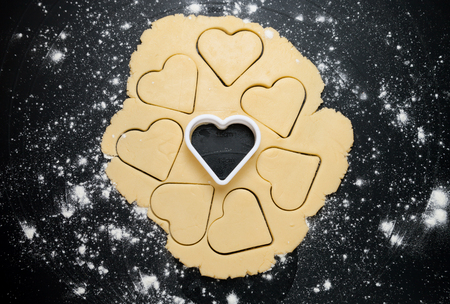 Heart shaped cookie cutter on dough preparing cookies conceptの写真素材