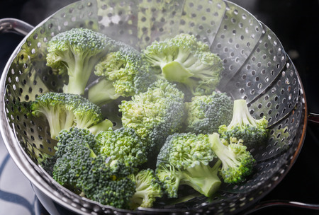 Freshly steamed green broccoli in skimmer pot with steam