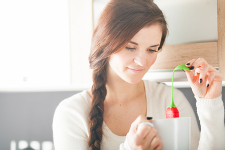 Woman with cup of tea in modern kitchenの写真素材