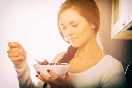 Woman with bowl of coco cereal, breakfast in homeの写真素材