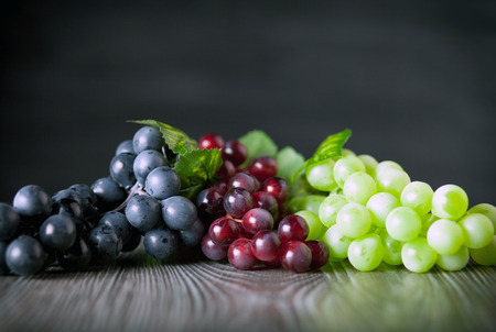 Colorful grape on wooden board dark background, copy spaceの写真素材