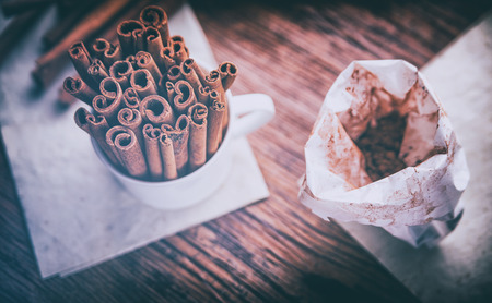 Cinnamon sticks and powder on rustic wooden board, top view