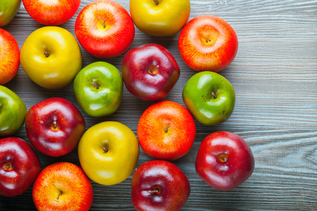 Ripe red green and yellow apples on wooden board, background