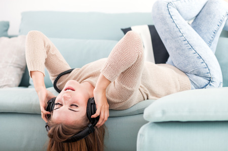 Young woman with headphones singing and listening to music at homeの写真素材