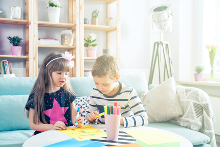Brother and sister drawing with colorful pencils together at homeの写真素材