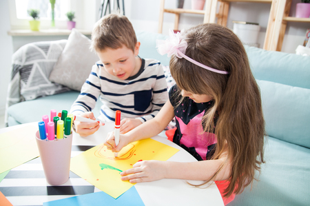 Brother and sister drawing with colorful pencils together at homeの写真素材