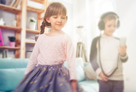 Little kids dancing and listening music at home, having fun togetherの写真素材