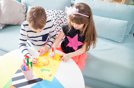 Brother and sister drawing with colorful pencils together at homeの写真素材