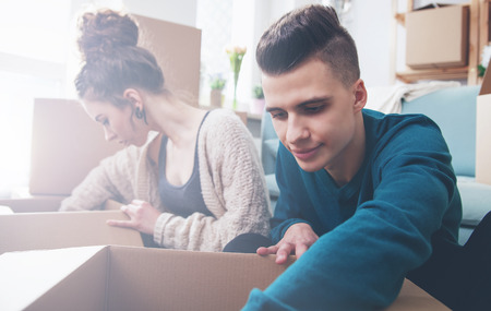 Young couple moving in new home and unpacking boxes