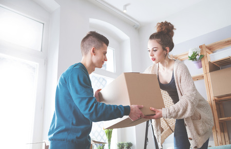 Young couple moving in new home and unpacking boxes