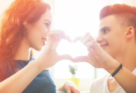 Young loving couple at home making heart shape with handsの写真素材