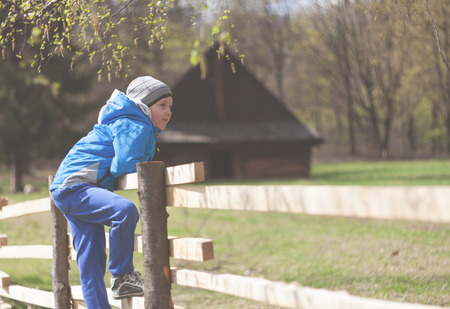 Little boy on fence in farm during early spring time, vintage filterの写真素材