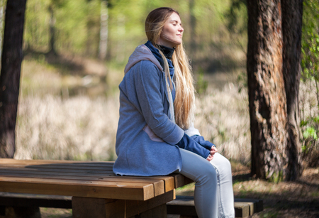 Woman enjoying sun sitting on bench in the parkの写真素材