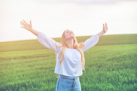 Happy smiling woman in green field at summer day, freedom conceptの写真素材