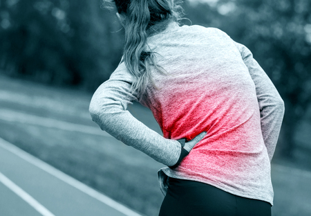 Athletic woman on running track has side cramps during workout