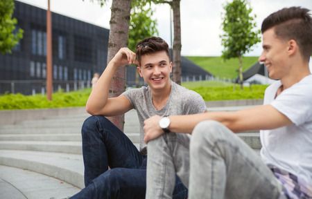 Two friends casual wear sitting on stairs in town and laughing, best friend conceptの写真素材