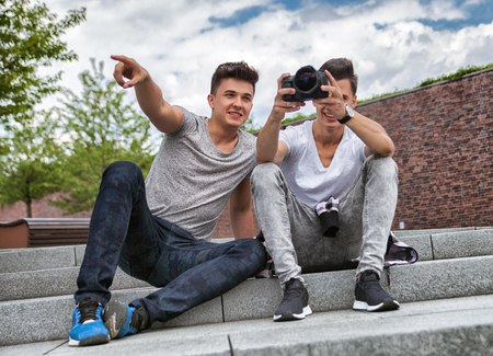 Two friends on stairs in town with camera and taking pictures, best friend conceptの写真素材