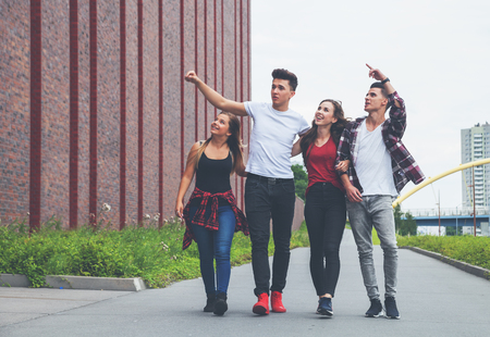 Group of friends walking together outdoor in the city, talking and laughingの写真素材