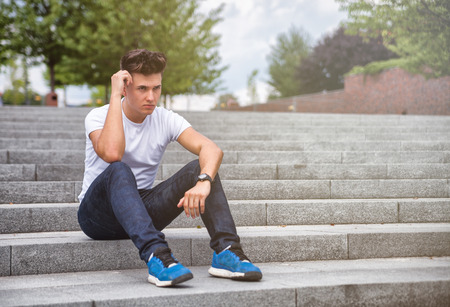 Handsome young man sitting outdoor on stairs in townの写真素材