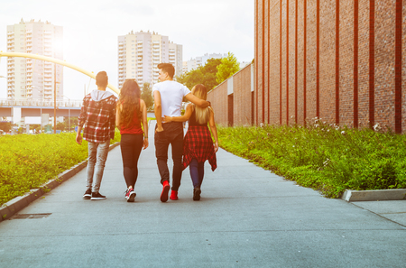 Group of friends walking together outdoor in the city, back viewの写真素材