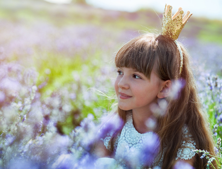 Cute princess child girl in crown on lavender field at summer day, happy childhood conceptの写真素材