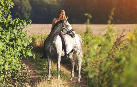 Woman riding a horse across farm at countrysideの写真素材
