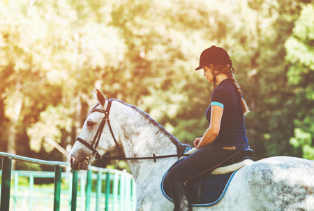 Young woman riding a horse, jockey in sportswearの写真素材