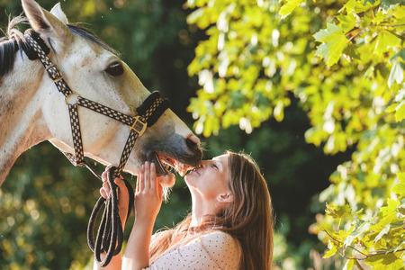 Woman kissing her horse at sunset, autumn outdoors sceneの写真素材