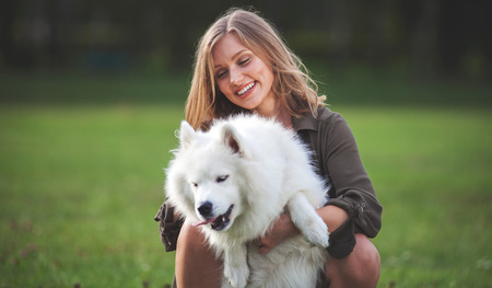 Portrait of smiling girl with her dog at the park outdoor, samoyedの写真素材
