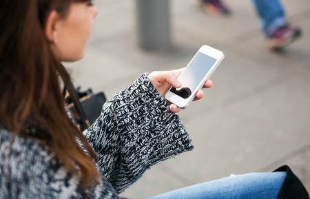 Close up of female hands with mobile phone using app on the streetの写真素材