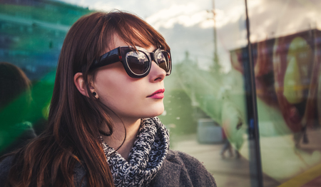 Close up fashion portrait of trendy woman in coat at the city street