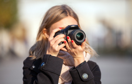 Tourist woman taking picture with camera during walk in the city