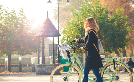 Girl in coat with vintage bike on the autumn streetの写真素材