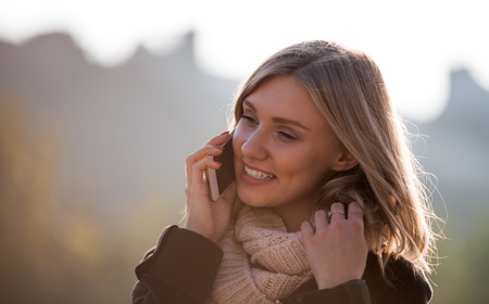 Beautiful young woman using phone at the city streetの写真素材
