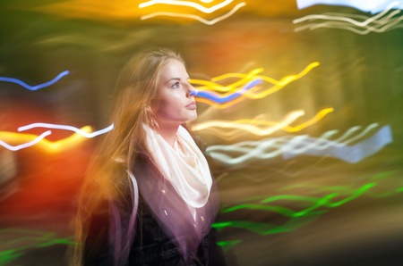 Woman in the city at night among neon moving lights
