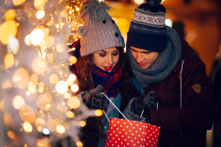 Happy couple in warm clothes enjoying colorul Christmas market, bokeh lights backgroundの写真素材