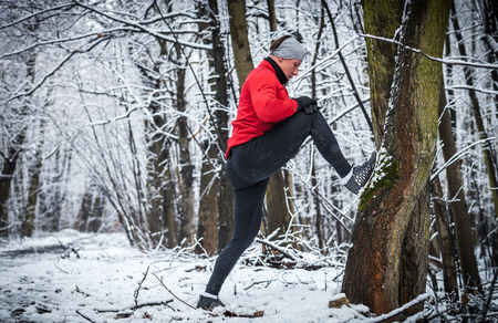 Winter running training, runner stretching at cold snowy forestの写真素材