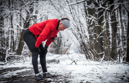 Winter running exercise, runner wearing warm sporty clothes has breakの写真素材